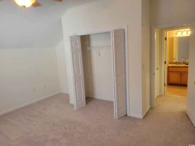 Unfurnished bedroom with light colored carpet, vaulted ceiling, a closet, and ceiling fan | Image 28