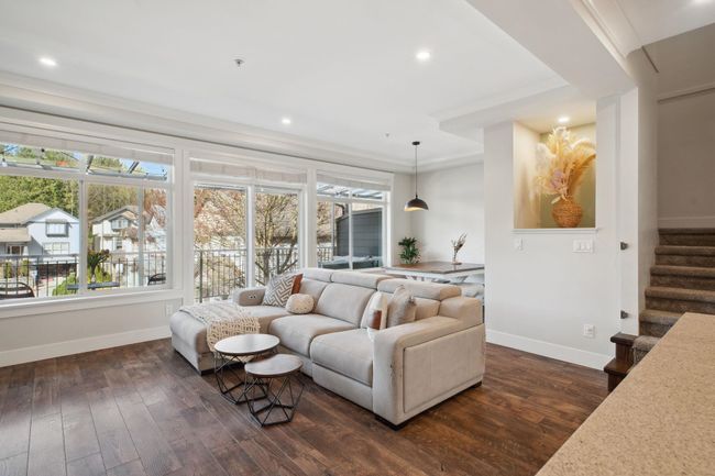 Living room with dark wood-type flooring, baseboards, and stairway | Image 6