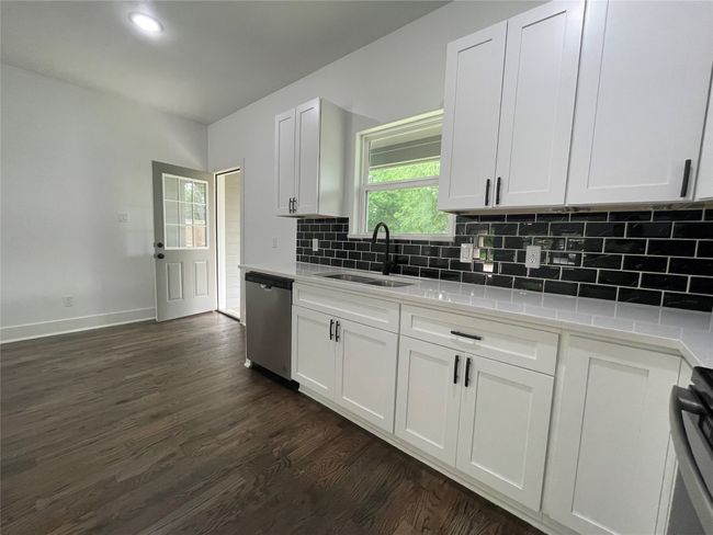 Kitchen with dishwasher, a sink, light countertops, decorative backsplash, and baseboards | Image 20
