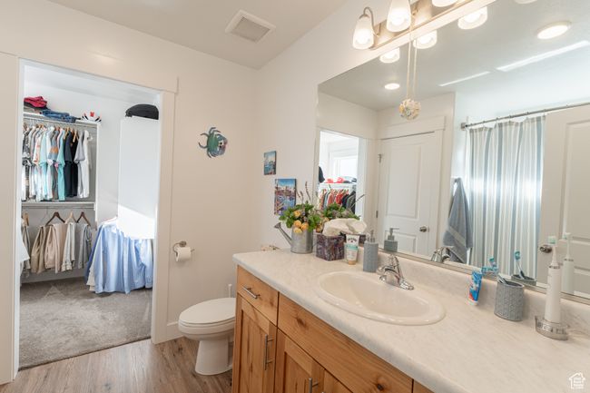 Full bathroom featuring visible vents, a shower with shower curtain, toilet, vanity, and wood finished floors | Image 11