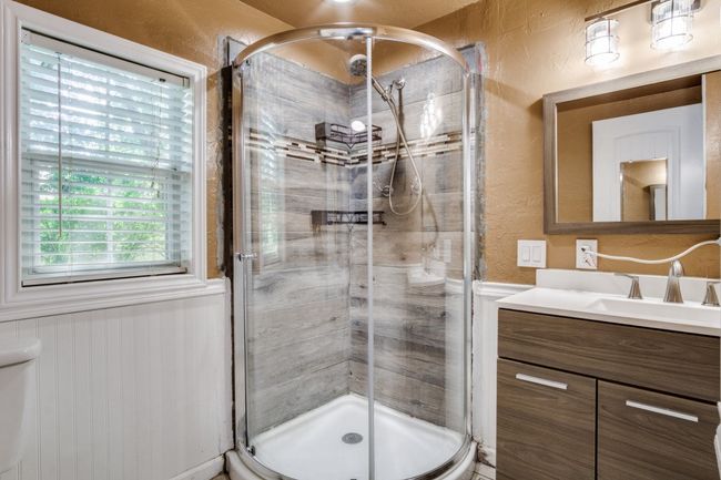 Bathroom featuring a textured wall, vanity, a shower stall, and a wainscoted wall | Image 22