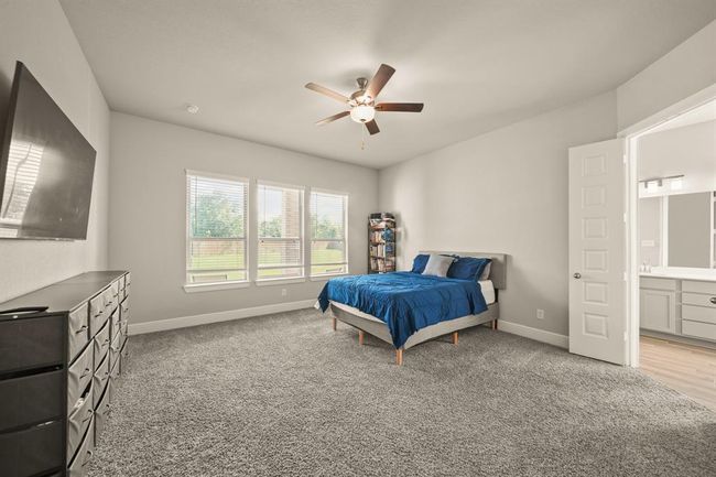 Welcome to the Elegant primary suite with plush carpeting, abundant natural light, and serene backyard views. | Image 16