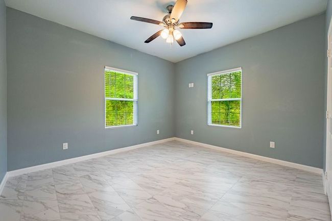 Empty room featuring marble finish floor, a wealth of natural light, baseboards, and a ceiling fan | Image 19