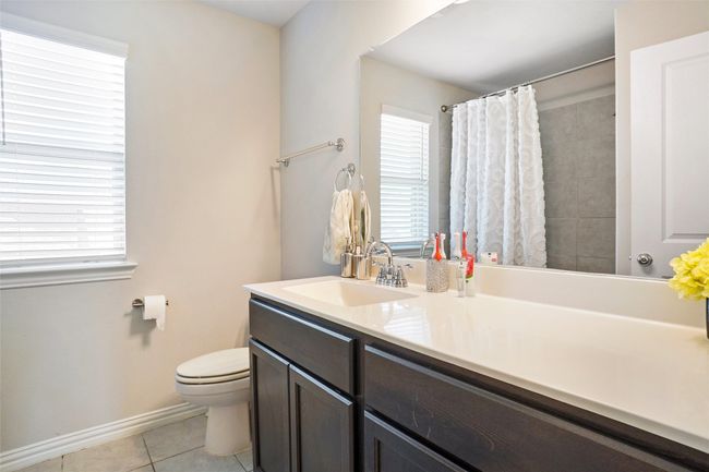 Full bathroom featuring tile patterned floors, toilet, vanity, baseboards, and a shower with shower curtain | Image 21