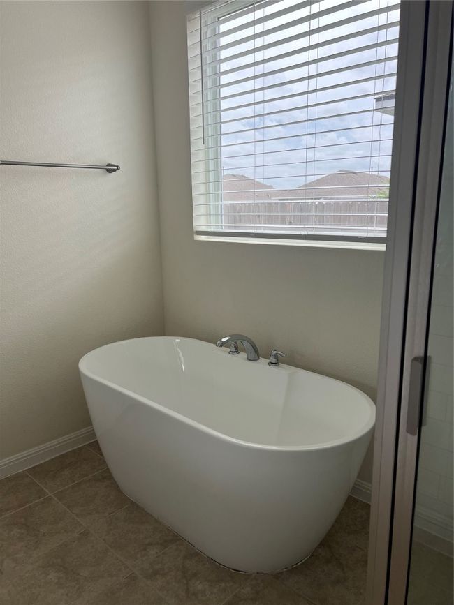 Natural light from this window bathes the Primary Bath with natural light featuring a luxurious freestanding soaking tub. | Image 12