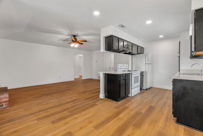 Kitchen with dark cabinets, a ceiling fan, electric range, light countertops, and recessed lighting | Image 14
