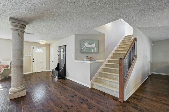Entrance foyer with ornate columns, stairway, hardwood / wood-style flooring, and a textured ceiling | Image 7
