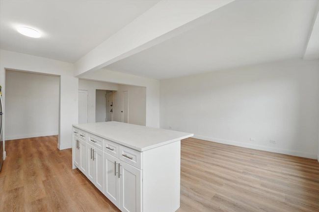 Kitchen featuring light countertops, light wood-style floors, baseboards, and white cabinetry | Image 11