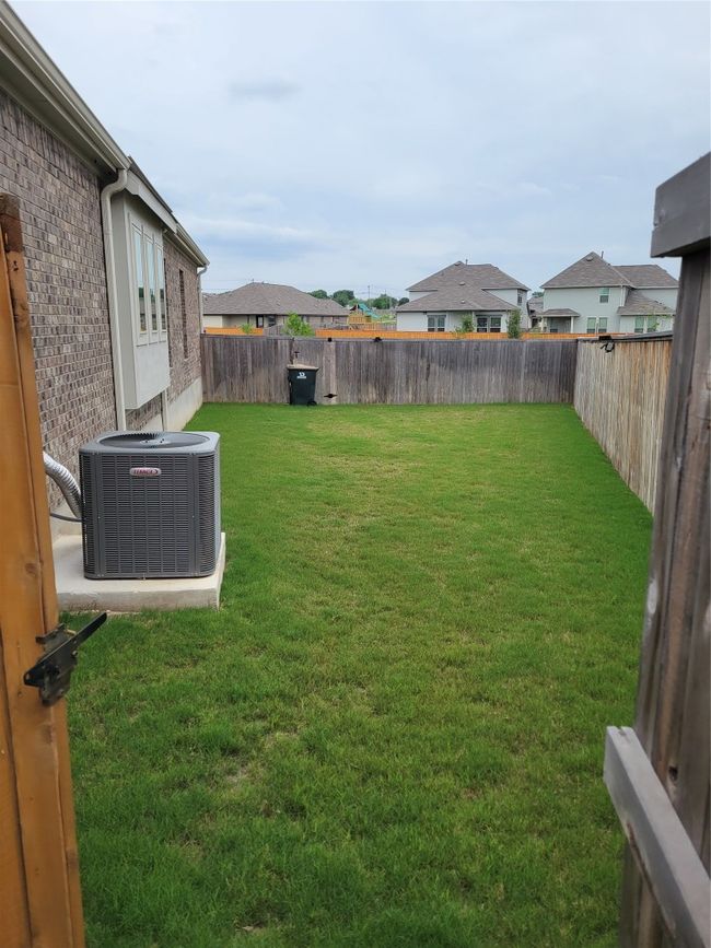 View of side yard featuring central air condition unit, a residential view, and a fenced backyard | Image 16