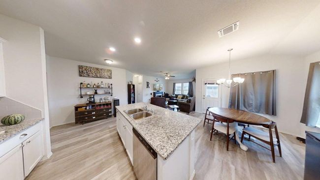 Kitchen featuring a sink, stainless steel dishwasher, light wood-style floors, and a center island with sink | Image 20