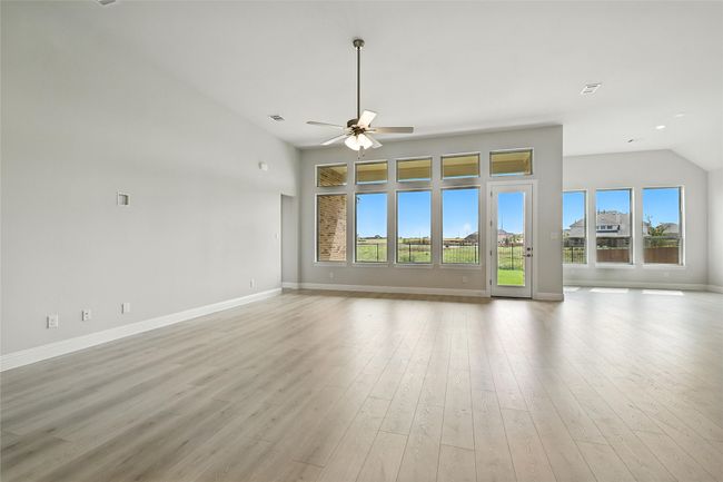 Unfurnished living room featuring healthy amount of natural light, ceiling fan, light wood-type flooring, and lofted ceiling | Image 11