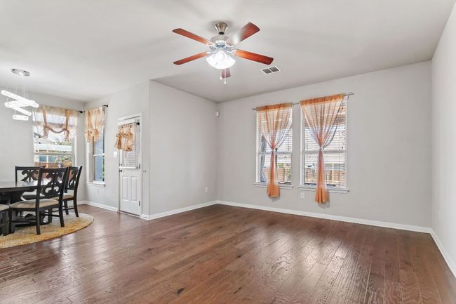Unfurnished living room with baseboards, visible vents, ceiling fan with notable chandelier, and wood-type flooring | Image 13
