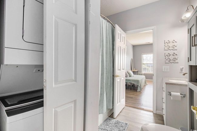 Bathroom featuring stacked washer / dryer, wood finished floors, vanity, and baseboards | Image 17