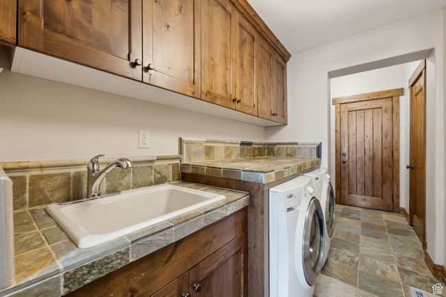 Laundry area with a sink, cabinet space, independent washer and dryer, and stone finish flooring | Image 28
