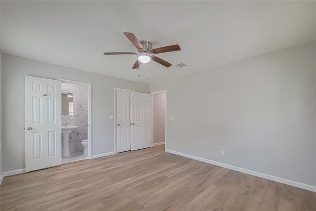 This restful primary bedroom has an en suite bath, ceiling fan, and ample room to personalize with your favorite furnishings. | Image 17