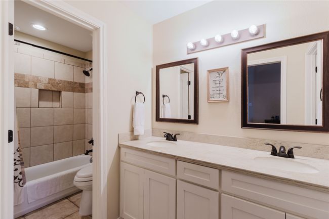 Full bathroom featuring tile patterned floors, shower / bath combo, toilet, and vanity | Image 11