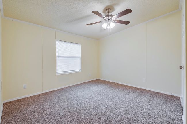Carpeted empty room featuring crown molding, a textured ceiling, and a ceiling fan | Image 14