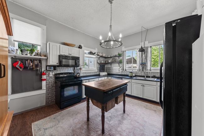 Kitchen featuring black appliances, dark countertops, a textured ceiling, a chandelier, and light wood-type flooring | Image 17