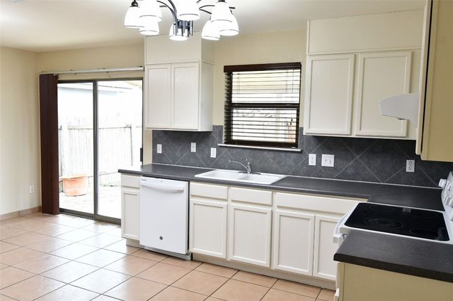 Kitchen featuring dark countertops, white appliances, tasteful backsplash, and a sink | Image 10