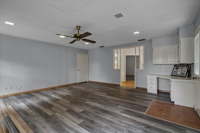 Unfurnished living room with dark wood-style flooring, ceiling fan, a textured ceiling, and built in desk | Image 25