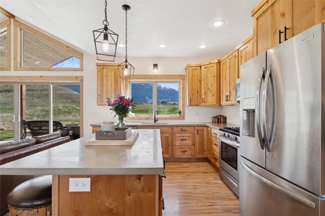 Kitchen featuring decorative light fixtures, a sink, light wood-type flooring, appliances with stainless steel finishes, and a kitchen island | Image 20