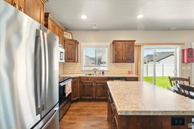 Kitchen with appliances with stainless steel finishes, dark wood finished floors, backsplash, light countertops, and recessed lighting | Image 6