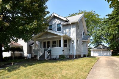 View of front of home with a garage, a front yard, a porch, and an outbuilding | Image 1