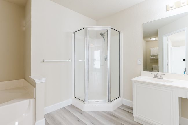 Bathroom featuring wood finished floors, a stall shower, a garden tub, and vanity | Image 10