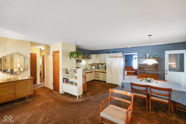 kitchen featuring white fridge with ice dispenser, open shelves, dark carpet, and light countertops | Image 13