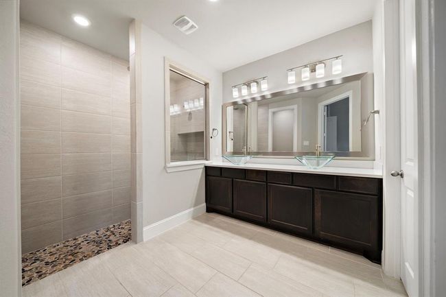 Upgraded primary bathroom featuring double vessel glass sinks and an oversized walk-in shower. | Image 15