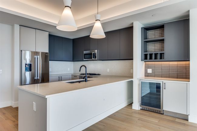 Kitchen featuring pendant lighting, tasteful backsplash, wine cooler, kitchen peninsula, and stainless steel appliances | Image 4