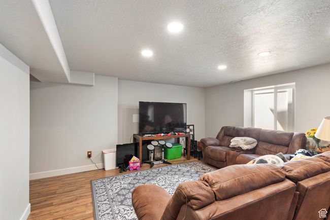 Living room with a textured ceiling, recessed lighting, wood finished floors, and baseboards | Image 21