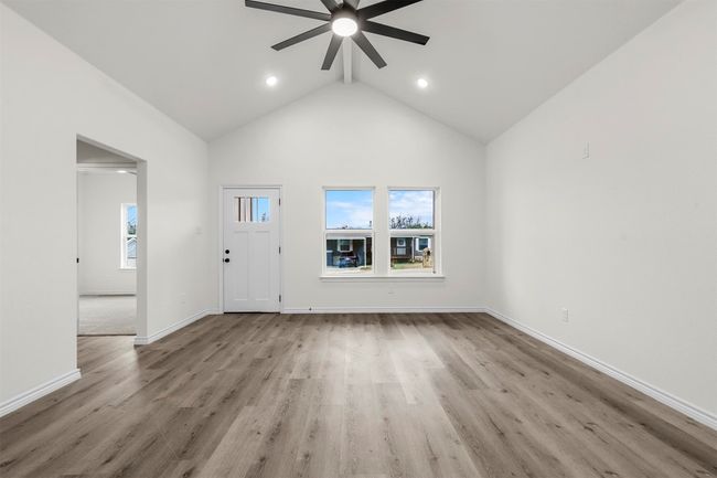Unfurnished living room featuring ceiling fan, light hardwood / wood-style floors, high vaulted ceiling, and a healthy amount of sunlight | Image 9