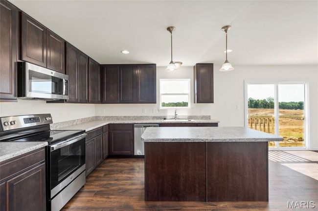 Kitchen featuring stainless steel appliances, plenty of natural light, dark brown cabinets, dark wood-type flooring, and recessed lighting | Image 9
