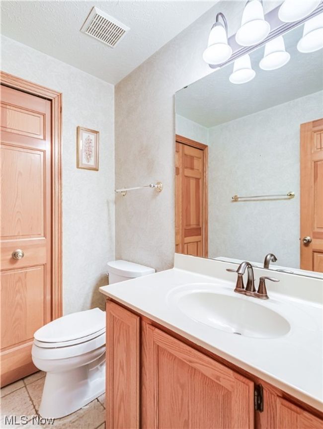 Bathroom with a textured ceiling, mirror, light tile floors, and vanity | Image 21
