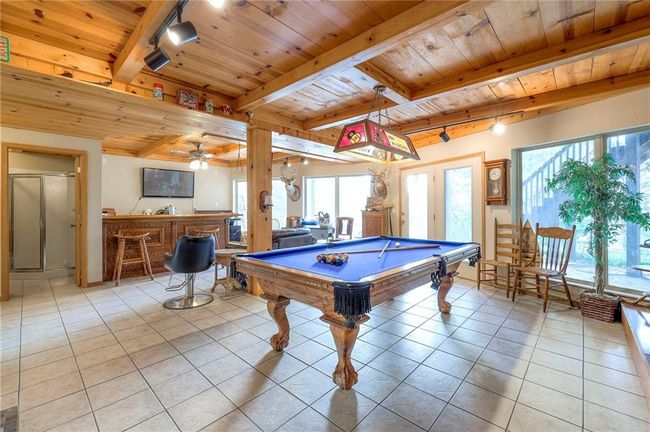 Game room with a wooden ceiling with exposed beams, light tile patterned flooring, pool table, healthy amount of natural light, and bar area | Image 38