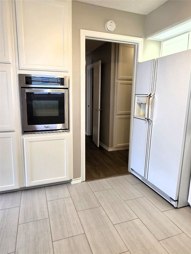Kitchen with white fridge with ice dispenser, oven, wood tiled floors, and baseboards | Image 16