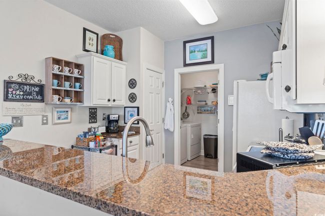 Kitchen featuring white cabinets, washing machine and clothes dryer, dark stone counters, and a textured ceiling | Image 12