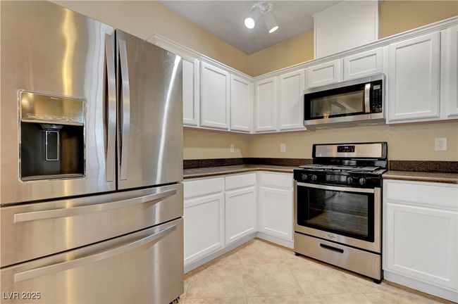Kitchen featuring white cabinets, light tile patterned flooring, and stainless steel appliances | Image 10