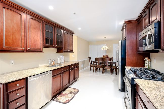Kitchen featuring stainless steel appliances, pendant lighting, glass insert cabinets, light stone counters, and recessed lighting | Image 13