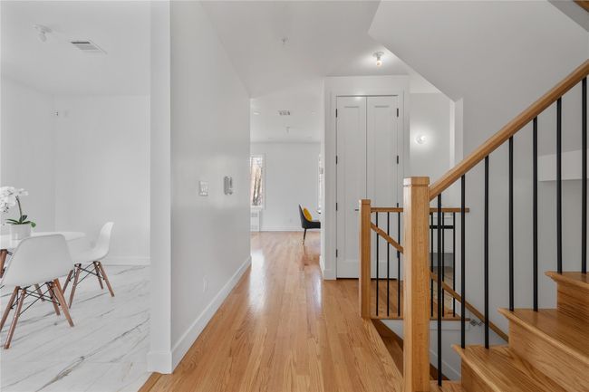 Hall featuring light wood finished floors, baseboards, visible vents, and stairway | Image 7