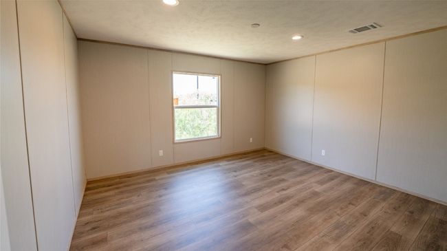 Empty room with light wood finished floors, recessed lighting, a decorative wall, and crown molding | Image 32