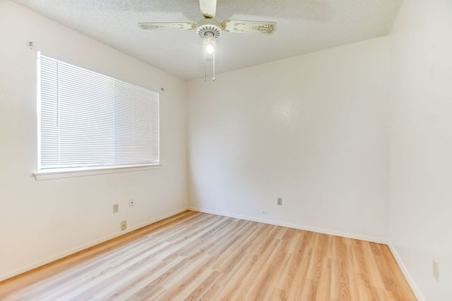 Spare room featuring wood finished floors, ceiling fan, baseboards, and plenty of natural light | Image 12