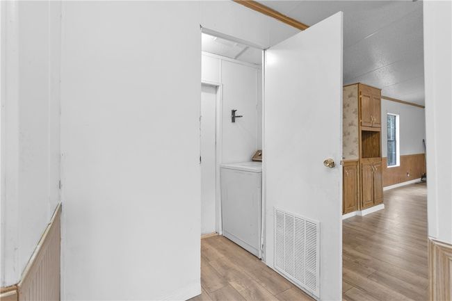 Hall featuring washer / dryer, light wood finished floors, and wainscoting | Image 9