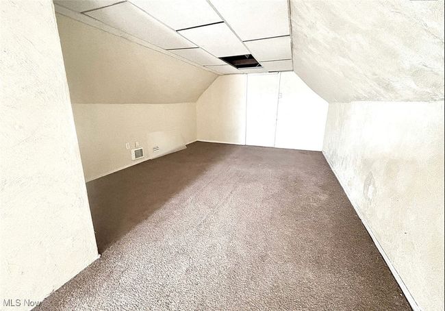 Additional living space featuring visible vents, a textured wall, vaulted ceiling, and carpet | Image 6