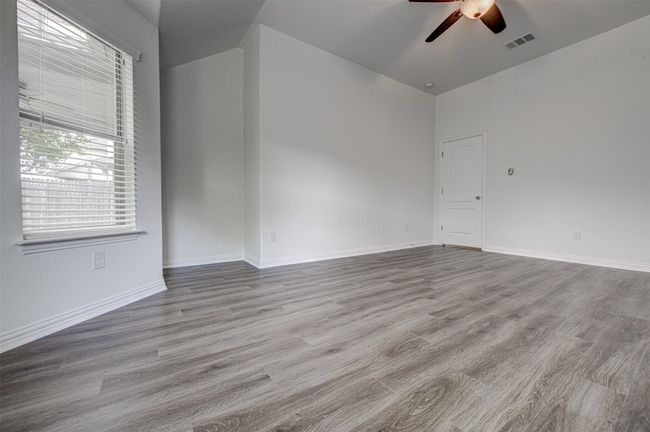 Spare room featuring a ceiling fan, wood finished floors, and a high ceiling | Image 17