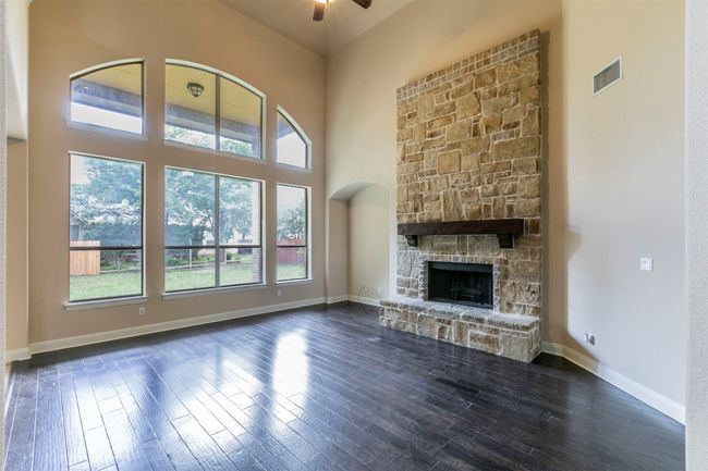 Unfurnished living room with a stone fireplace, dark wood floors, and soaring ceiling | Image 9