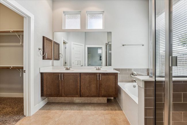 Full bath with healthy amount of natural light, a bath, double vanity, a spacious closet, and a high ceiling | Image 18