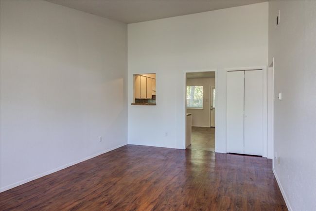Empty room with dark wood-type flooring, a towering ceiling, and baseboards | Image 5