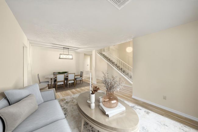 Open-concept living and dining space features a large seating area, neutral flooring, and direct access to the staircase. This photo has been virtually staged. | Image 8